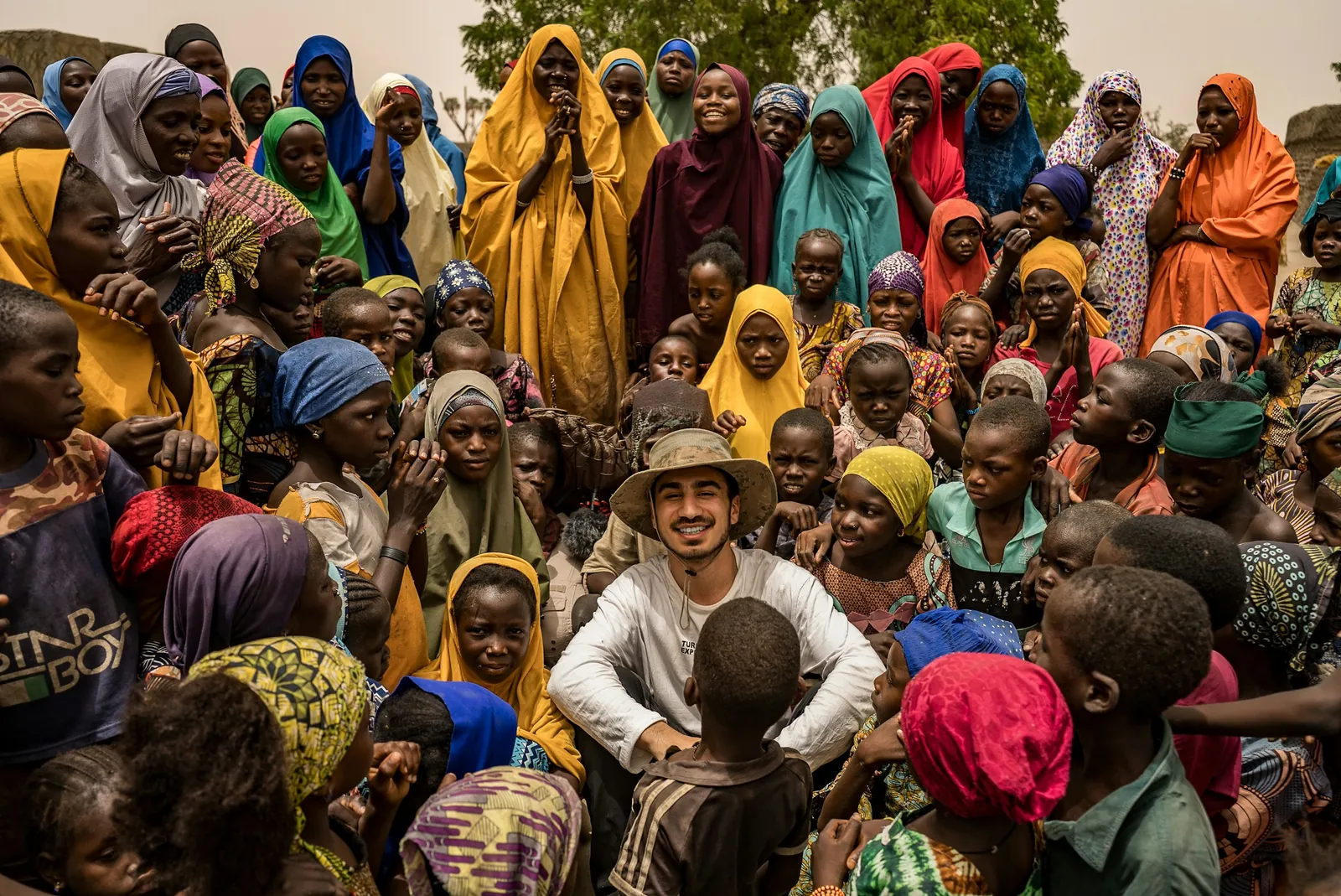 A relief worker sitting among a large crowd of women and children