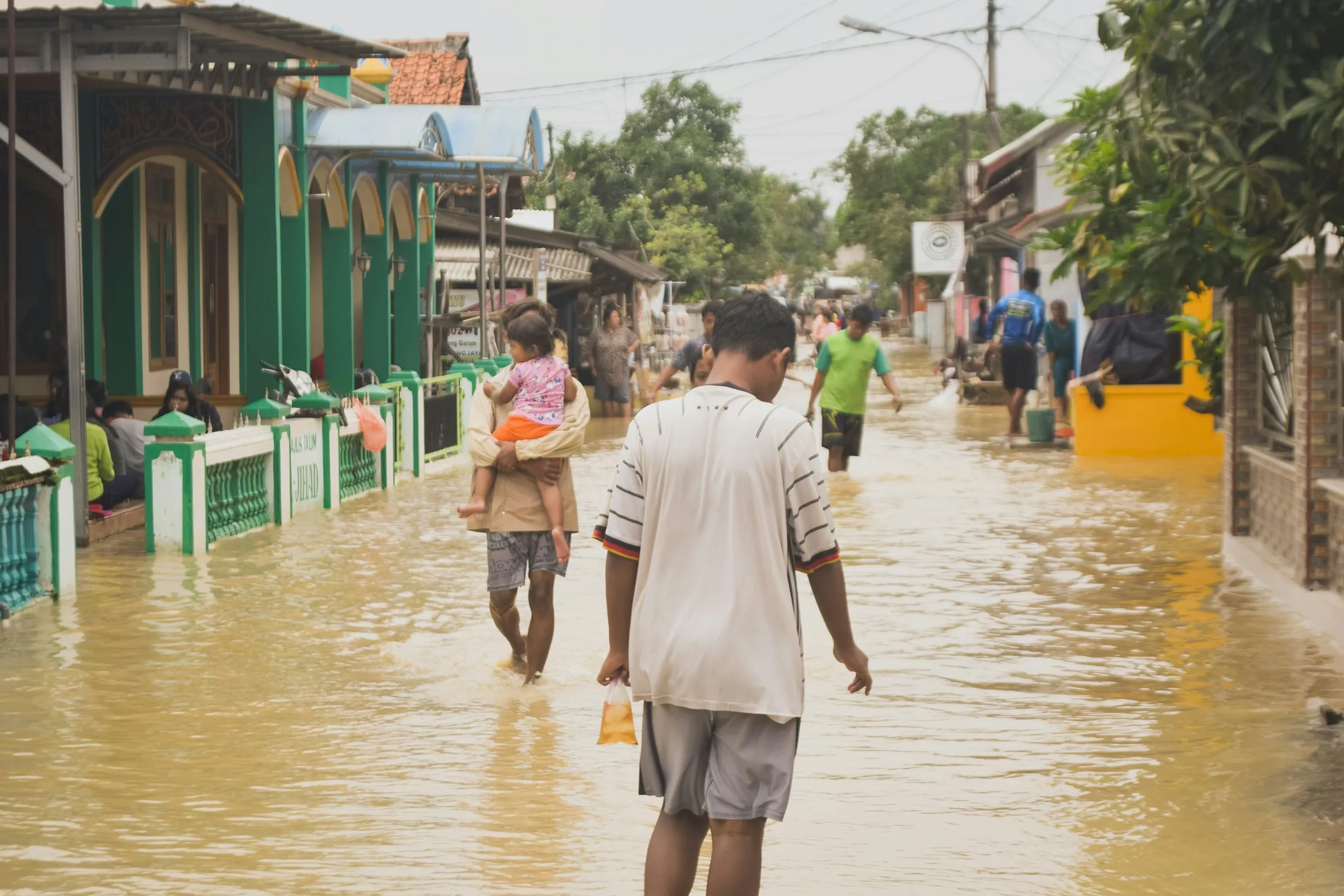 A man carrying a child through floodwater